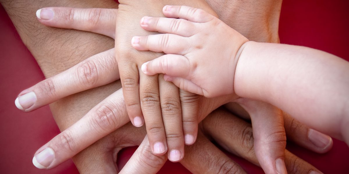 Four hands of the family, a baby, a daughter, a mother and a father. Concept of unity, support, protection and happiness.